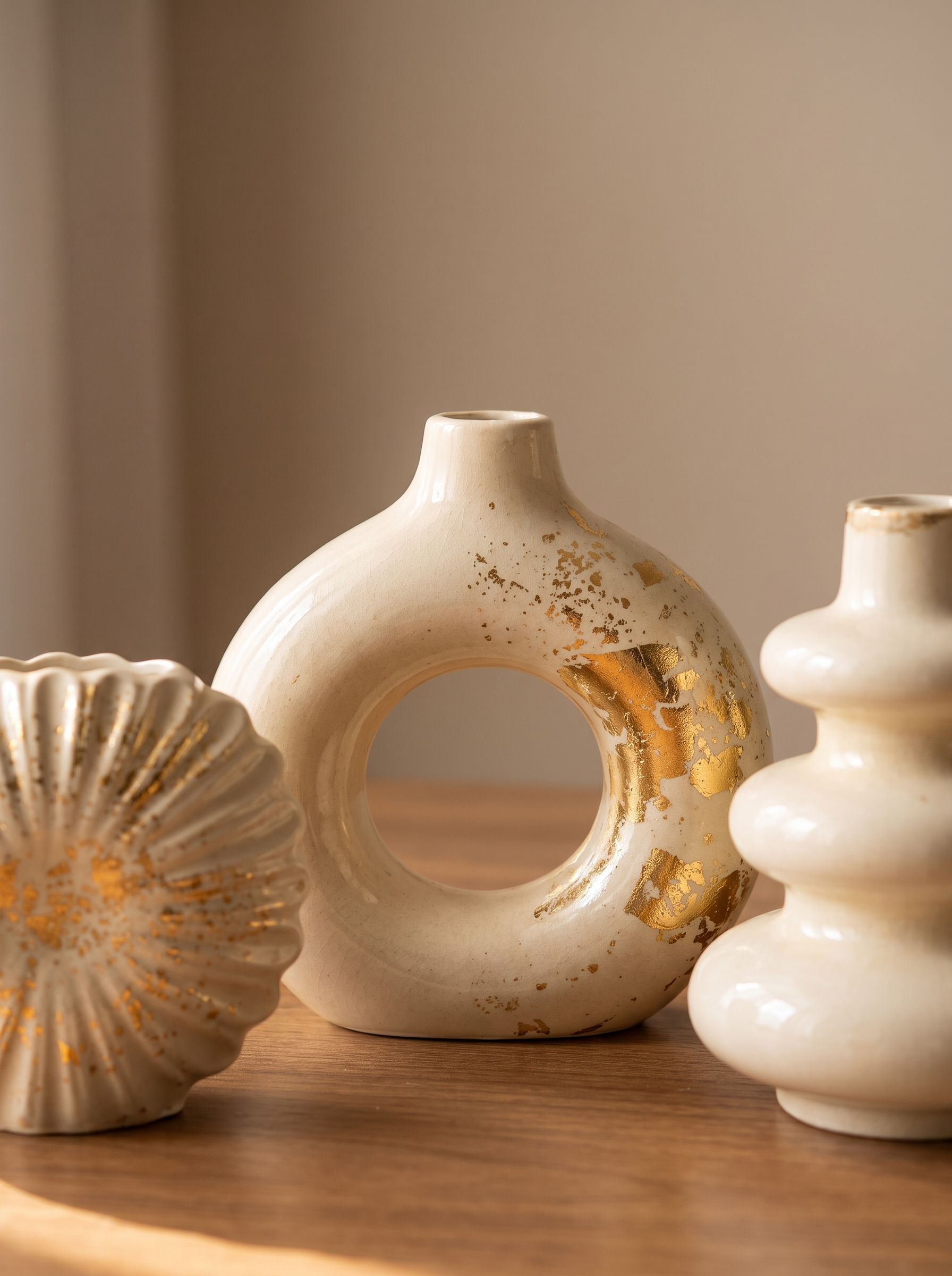 Close-up of ceramic vase set showing gold-leaf splatter texture on ring, shell and bubble shaped vases